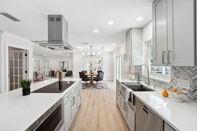 kitchen featuring sink, gray cabinetry, stainless steel appliances, island range hood, and decorative backsplash