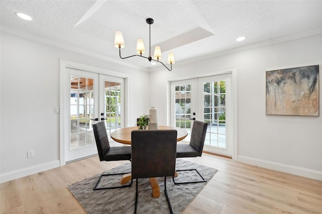 dining area with ornamental molding, a textured ceiling, light hardwood / wood-style floors, and french doors