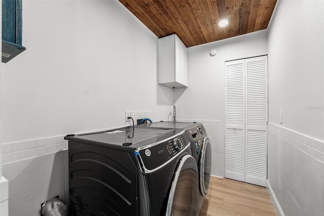 laundry room featuring independent washer and dryer, cabinets, light hardwood / wood-style floors, and wooden ceiling