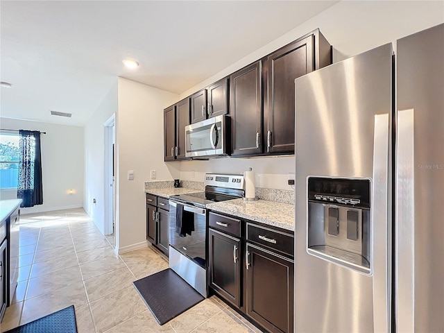 kitchen featuring appliances with stainless steel finishes, light stone countertops, dark brown cabinets, and light tile patterned floors