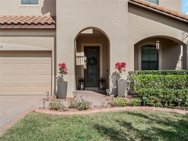 view of exterior entry with a yard and a garage