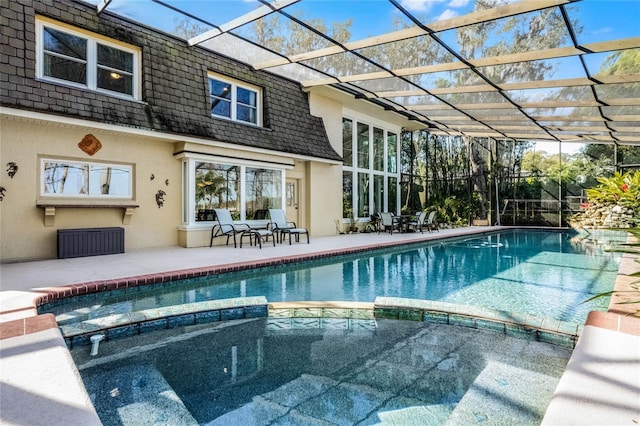 view of pool with an in ground hot tub, a patio, and glass enclosure