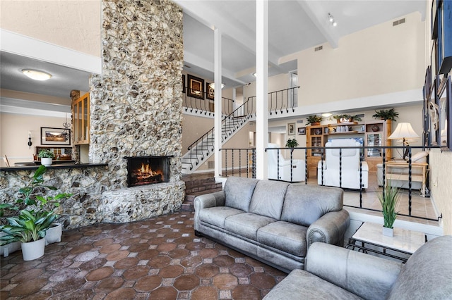 living room featuring beam ceiling, a fireplace, and a towering ceiling