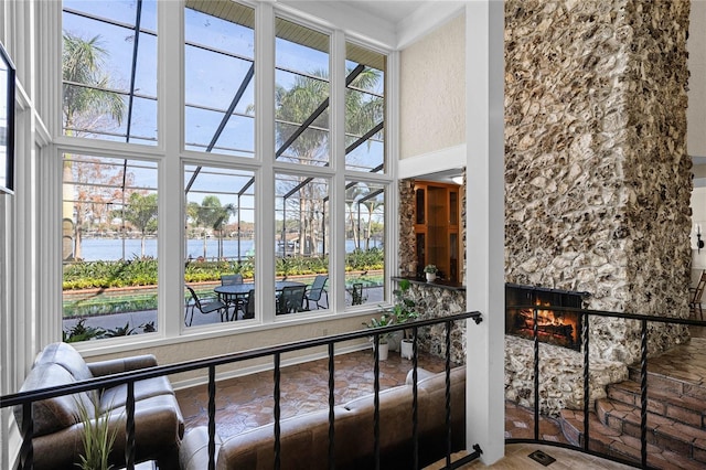 sunroom / solarium with a water view and a stone fireplace