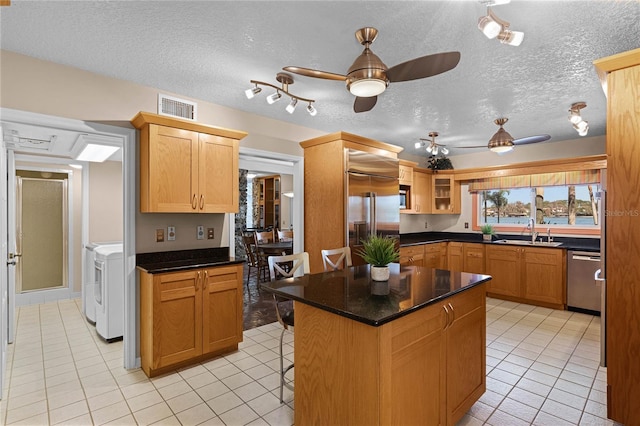 kitchen featuring sink, a center island, stainless steel dishwasher, light tile patterned floors, and ceiling fan