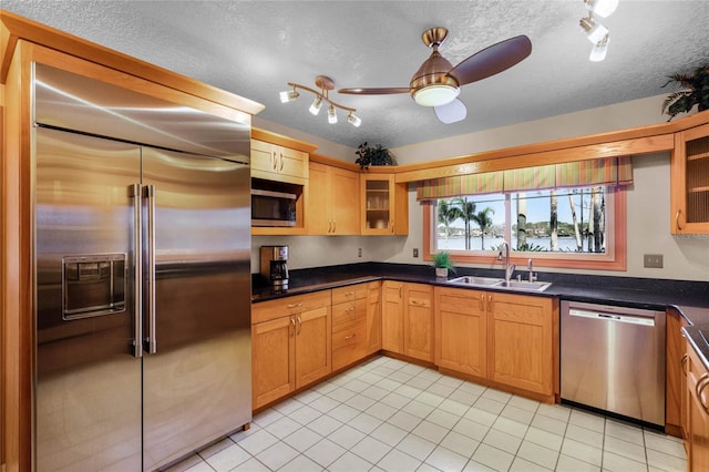 kitchen featuring sink, a textured ceiling, light tile patterned floors, ceiling fan, and stainless steel appliances