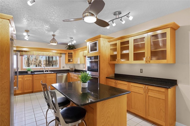 kitchen featuring light tile patterned floors, a breakfast bar area, ceiling fan, stainless steel appliances, and a kitchen island