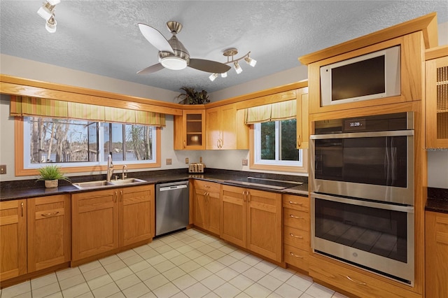 kitchen featuring ceiling fan, stainless steel appliances, sink, and a textured ceiling