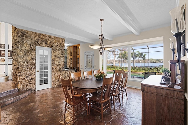 dining room with crown molding, beam ceiling, a textured ceiling, and a water view