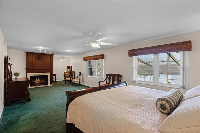 carpeted bedroom featuring ceiling fan, multiple windows, and a textured ceiling