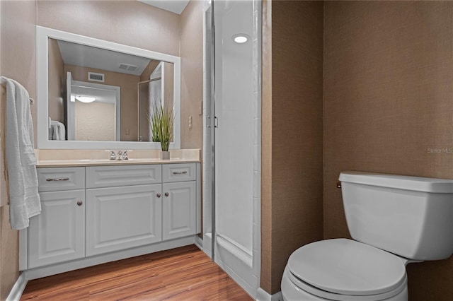 bathroom featuring hardwood / wood-style flooring, vanity, a shower, and toilet