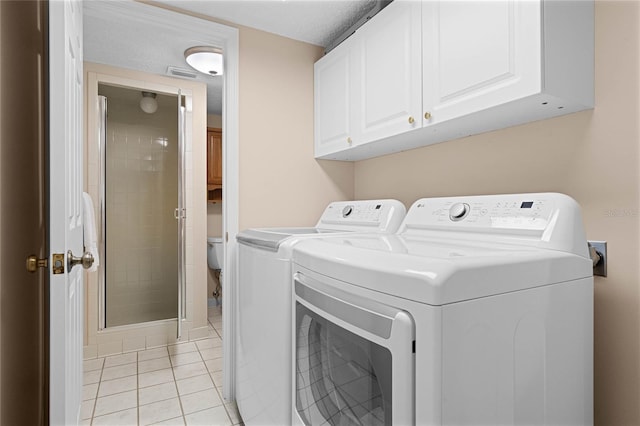 washroom featuring cabinets, washing machine and dryer, and light tile patterned floors