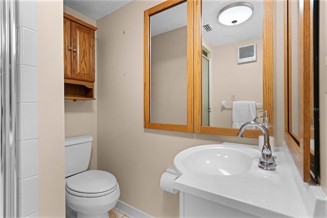 bathroom with vanity, toilet, and a textured ceiling