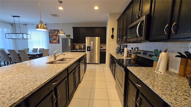 kitchen with appliances with stainless steel finishes, decorative light fixtures, sink, decorative backsplash, and light stone countertops