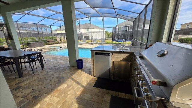 view of patio with grilling area, an in ground hot tub, and an outdoor kitchen