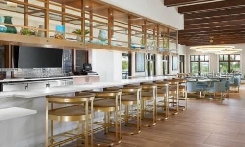 bar featuring beamed ceiling, a towering ceiling, and hardwood / wood-style flooring