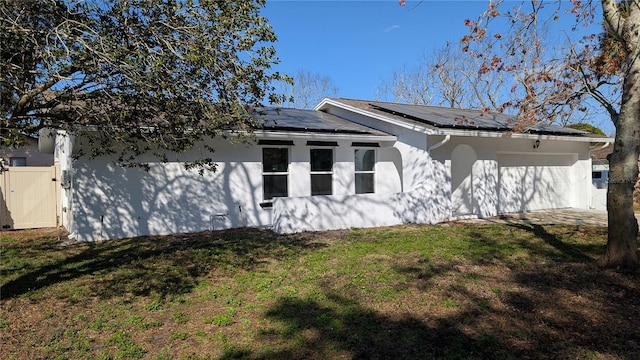 view of side of property featuring a garage, a yard, and solar panels