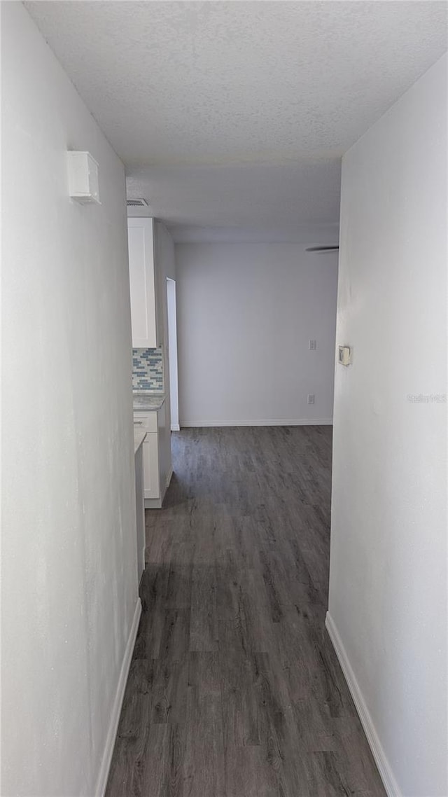 hall with dark hardwood / wood-style flooring and a textured ceiling