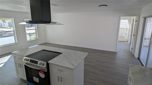 kitchen featuring light stone counters, island range hood, stainless steel electric stove, and white cabinets