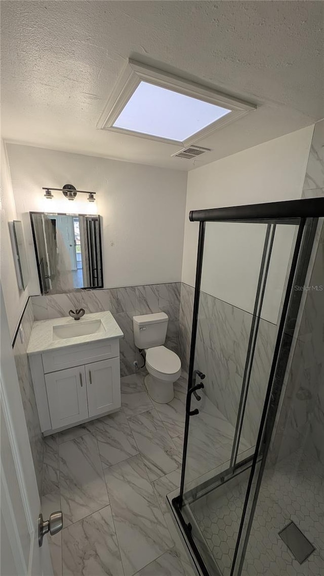 bathroom with vanity, toilet, an enclosed shower, and a textured ceiling