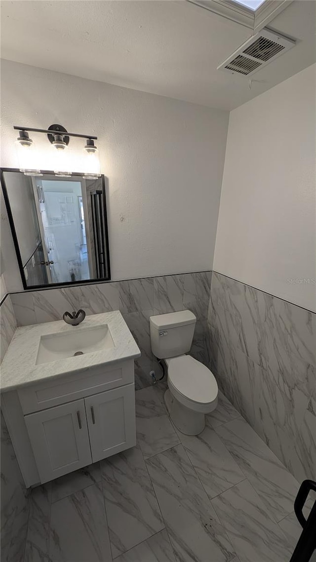 bathroom featuring tile walls, vanity, and toilet