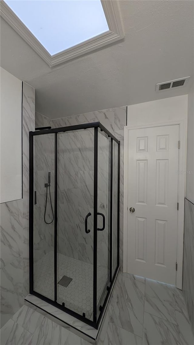 bathroom featuring a skylight and a shower with shower door