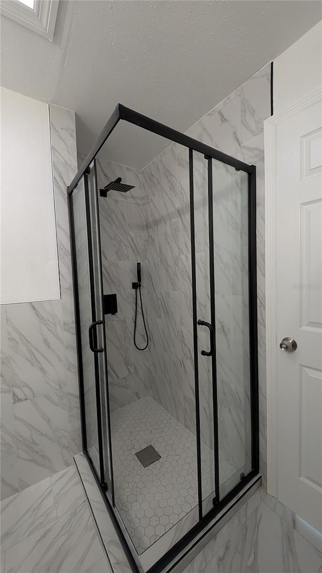 bathroom featuring a shower with door and a textured ceiling