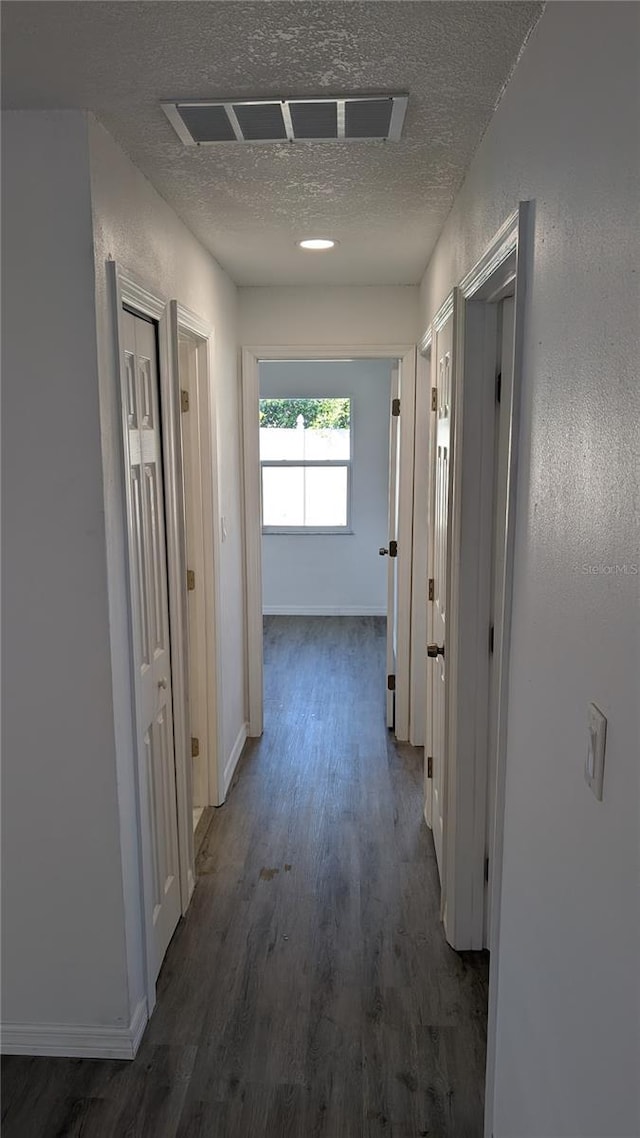 corridor featuring dark hardwood / wood-style flooring and a textured ceiling