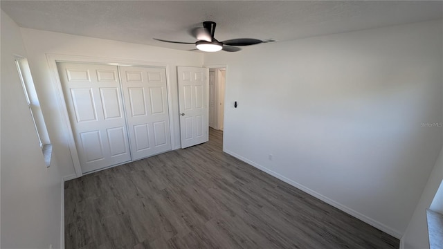 unfurnished bedroom featuring ceiling fan, dark wood-type flooring, a textured ceiling, and a closet