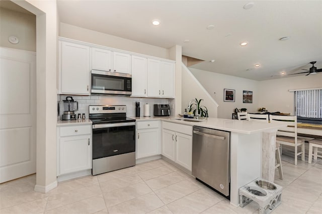 2623 Buena View Rd, Kissimmee, FL 34746 - kitchen featuring appliances with stainless steel finishes, a sink, a peninsula, decorative backsplash, and white cabinetry