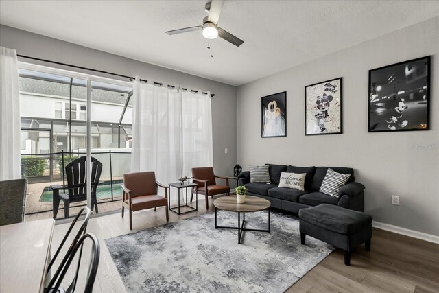 living area with ceiling fan, wood finished floors, and baseboards