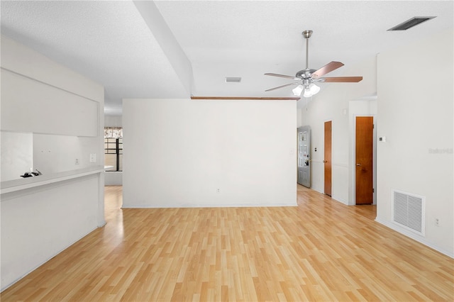 spare room featuring ceiling fan, vaulted ceiling, light hardwood / wood-style flooring, and a textured ceiling