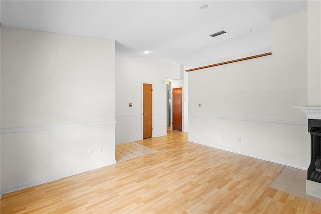 unfurnished living room with lofted ceiling, light hardwood / wood-style floors, and a multi sided fireplace