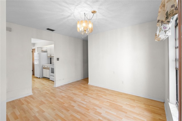 interior space featuring a textured ceiling, a chandelier, and light wood-type flooring