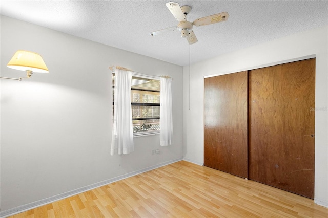 unfurnished bedroom featuring ceiling fan, a textured ceiling, light wood-type flooring, and a closet