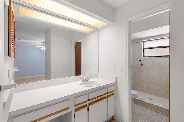 bathroom featuring vanity, ceiling fan, toilet, and tiled shower