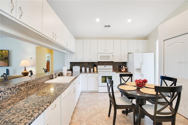 kitchen featuring white cabinetry, sink, white appliances, and dark stone counters