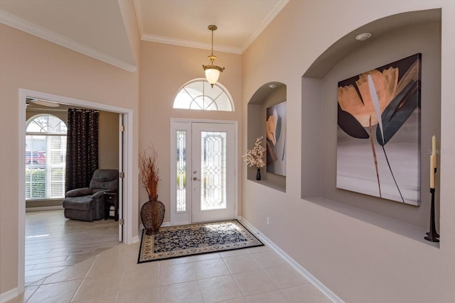 foyer with crown molding, a towering ceiling, and light tile patterned floors