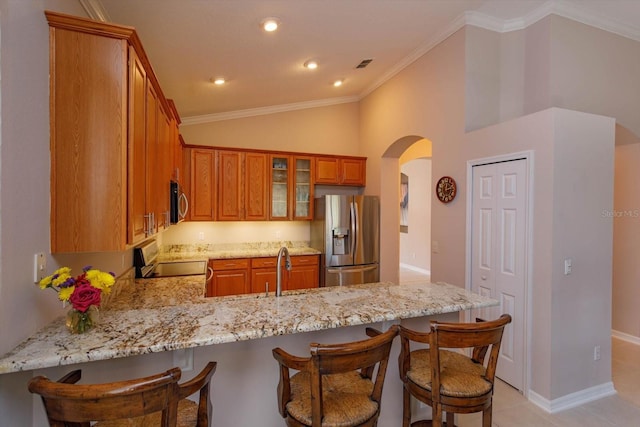 kitchen featuring lofted ceiling, light stone counters, ornamental molding, kitchen peninsula, and stainless steel appliances