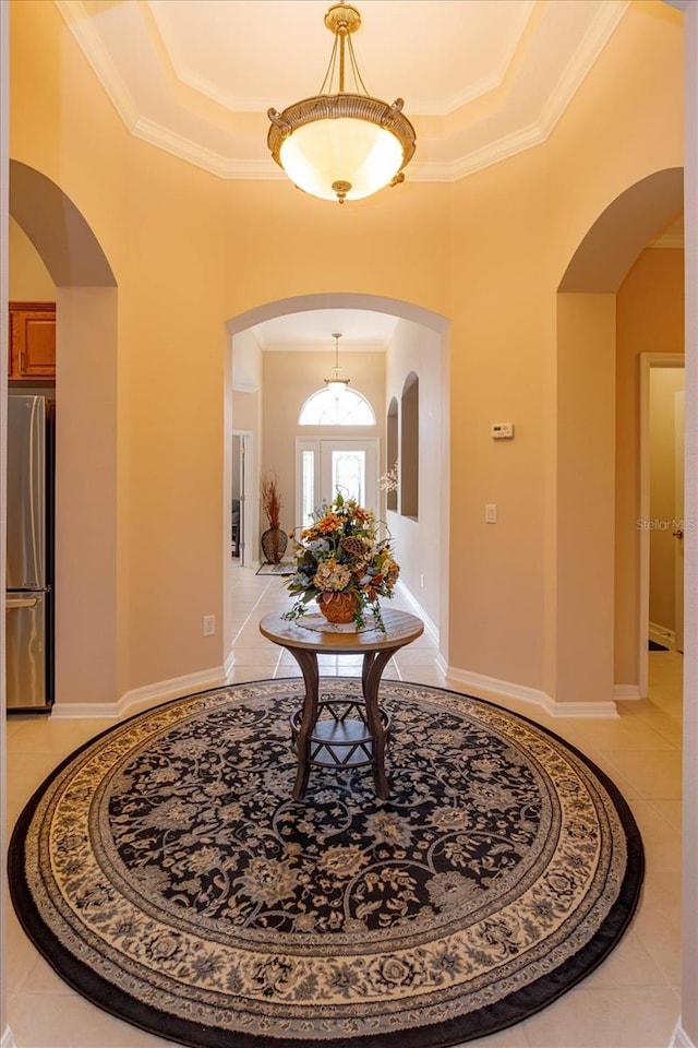 entryway featuring crown molding, a tray ceiling, and light tile patterned floors