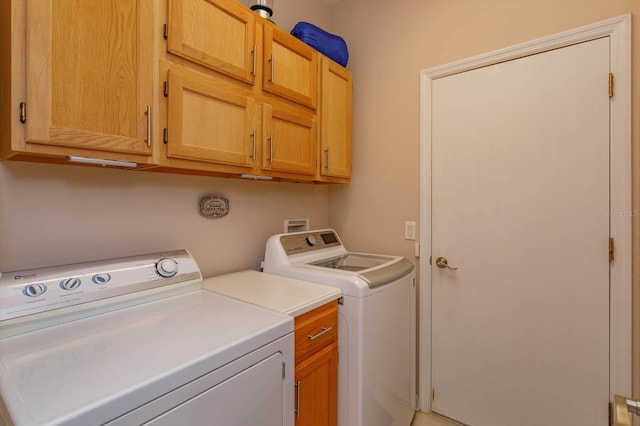 clothes washing area featuring cabinets and independent washer and dryer