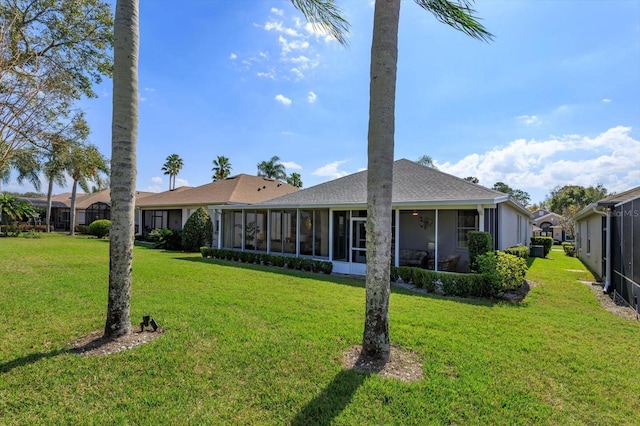 rear view of house with a sunroom and a lawn