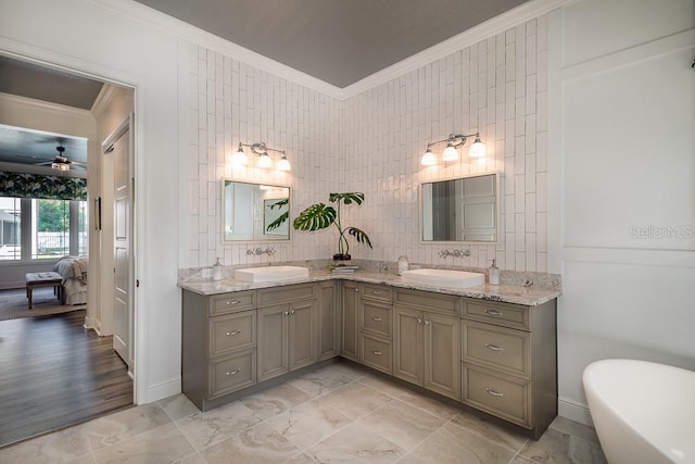 bathroom featuring tile walls, a tub to relax in, vanity, ceiling fan, and crown molding