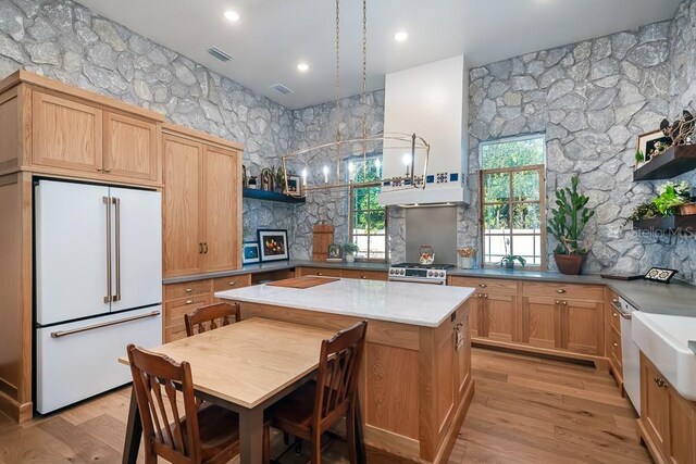 kitchen with gas range, light brown cabinetry, high end fridge, and light wood-type flooring