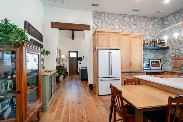 kitchen featuring light hardwood / wood-style flooring, a high ceiling, a fireplace, light brown cabinetry, and high end white fridge