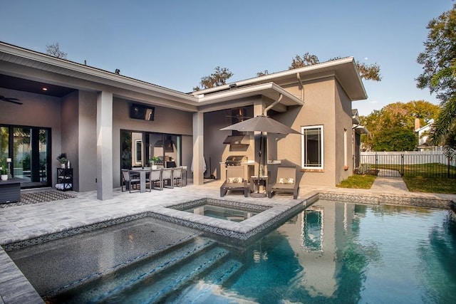 rear view of house featuring a swimming pool with hot tub, a patio, and exterior kitchen