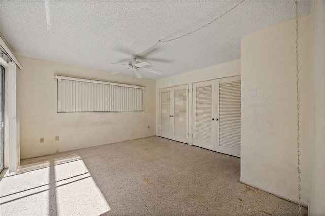 unfurnished bedroom featuring ceiling fan, two closets, and a textured ceiling