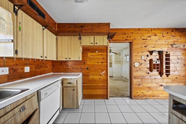 kitchen with light tile patterned floors, a textured ceiling, wooden walls, and dishwasher