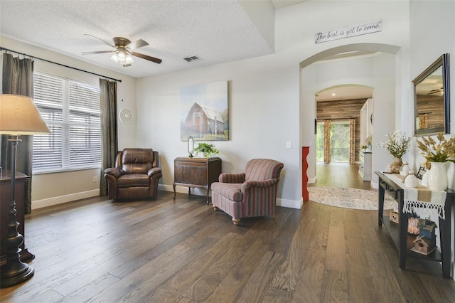 sitting room with ceiling fan, dark wood-type flooring, and a textured ceiling