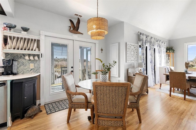 dining room featuring light hardwood / wood-style flooring, french doors, a chandelier, and vaulted ceiling